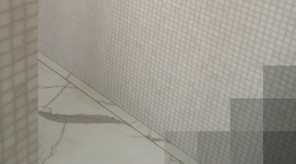 Een douche waarvan de vloer afgewerkt is in callacatta, de muren zijn dan weer in marmermozaïek.